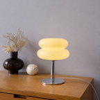 Yellow sculptural glass table lamp glowing beside neutral decor.