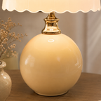 Close view of the yellow ceramic base and polished gold neck of a table lamp.