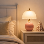 A pink half dome table lamp glows on a compact bedside cabinet.