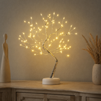 Tree of Light table lamp glowing between decorative objects on a console.