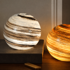 Two glass moon table lamps glowing white and amber on a dark wood console.