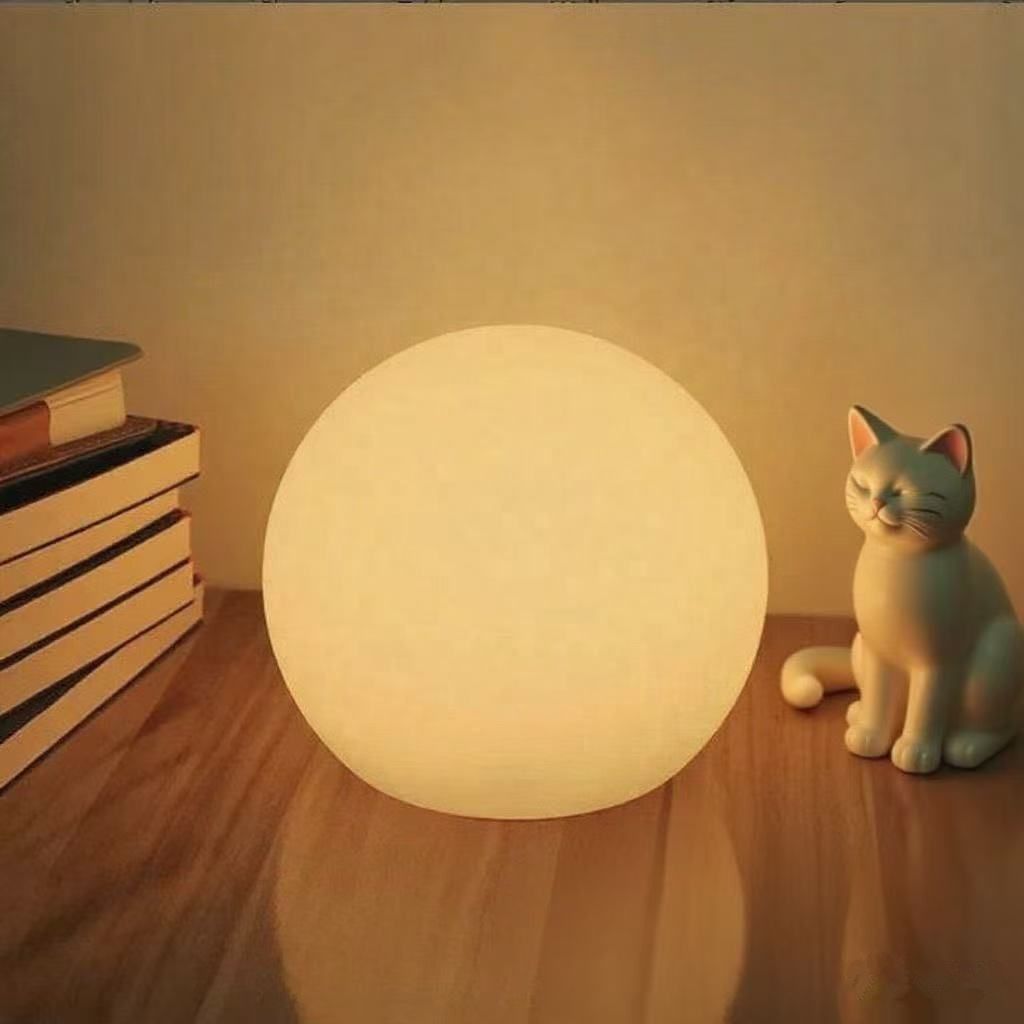 Moon table lamp glowing orange in a dark room.