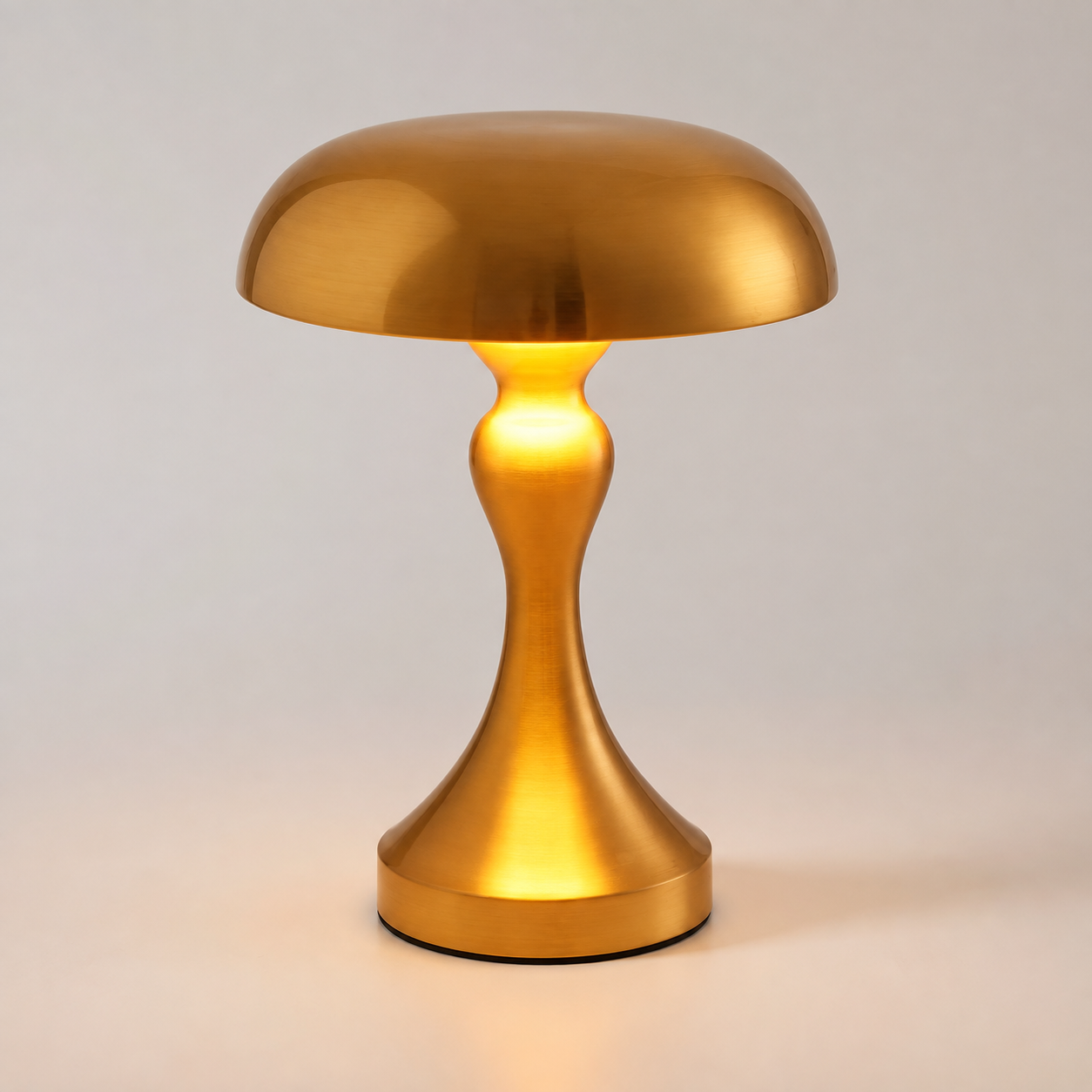 Gold table lamp glowing against a light gray studio background.