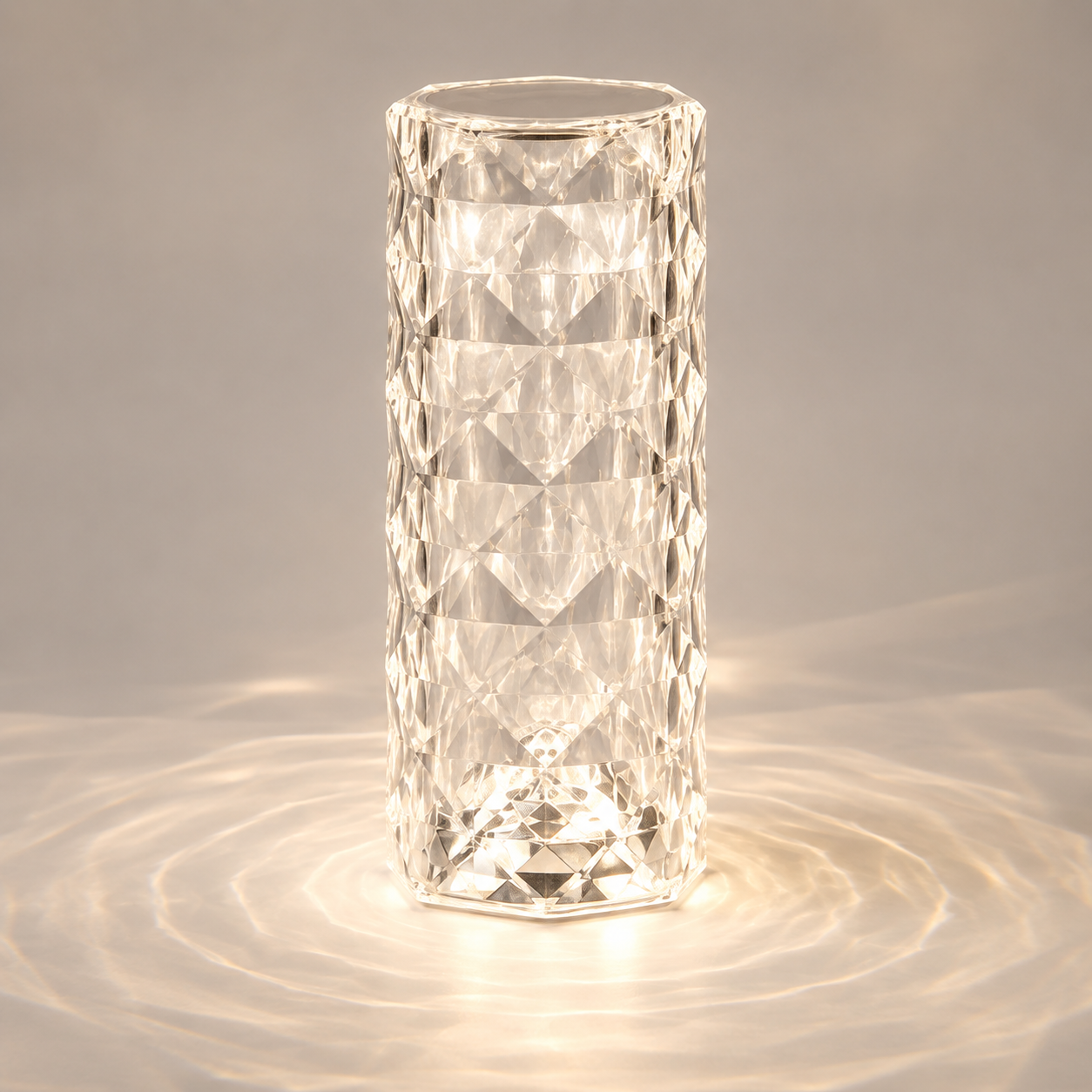 Clear faceted table lamp glowing on a gray surface with circular light patterns around the base.