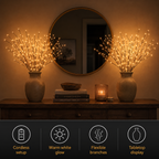 A lighted branch vase glows on a wooden console beside stacked books and decorative objects.
