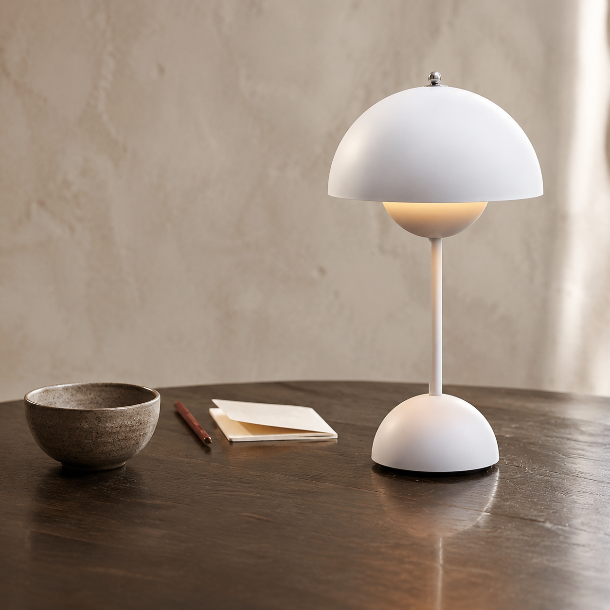 white dome table lamp glowing on a dark wood table