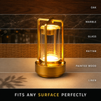 Gold lantern table lamp displayed on oak, marble, glass, rattan, painted wood, and linen surfaces.