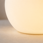 Macro close-up of the table lamp's smooth glowing surface and rounded lower edge.