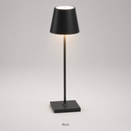Black table lamp with a tapered shade, slim stem, square base and warm light on a plain background.