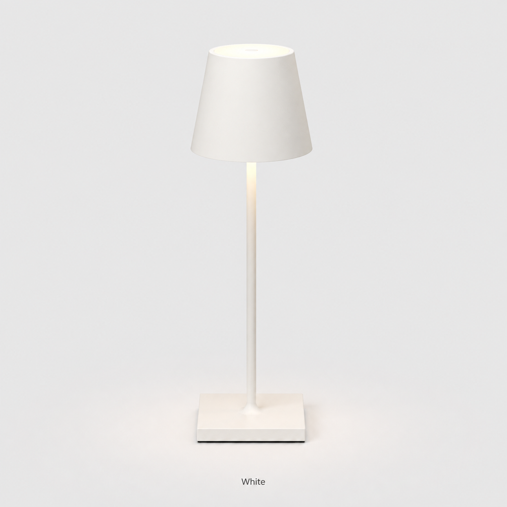 White table lamp with a tapered shade, slim stem, square base and warm light on a plain background.