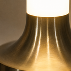 Close-up of the gold table lamp base showing its curved metallic surface and warm glow.