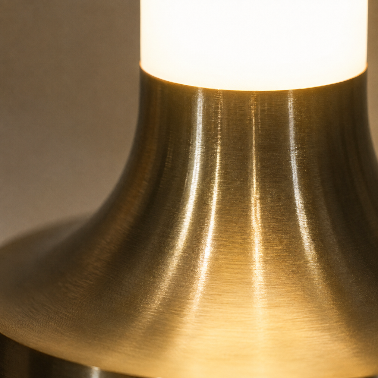 Close-up of the gold table lamp base showing its curved metallic surface and warm glow.