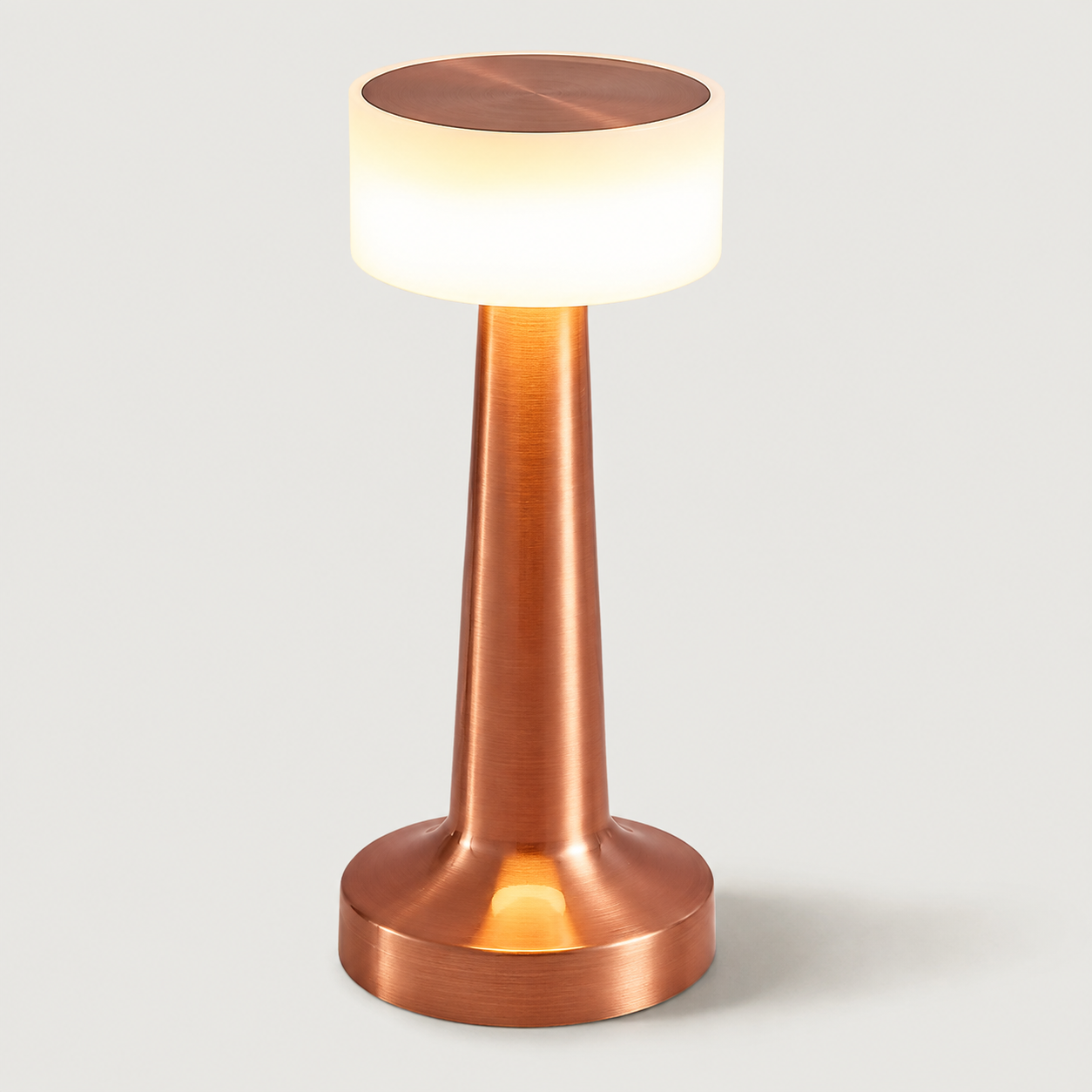 Rose gold table lamp with a glowing white shade on a plain light background.