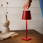 red rechargeable table lamp operated by a hand on a wood table