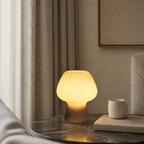 Smoke gray ribbed glass mushroom table lamp beside books.