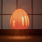 Table lamp with an orange shade glowing against a dark paneled wall.