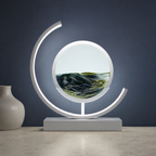 Black quicksand table lamp with a white frame glowing against a muted navy wall.