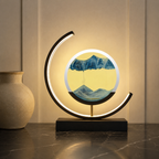 Blue quicksand table lamp with a black frame glowing in a sand-toned setting.