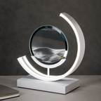 Black quicksand table lamp with a white curved frame on a gray tabletop.