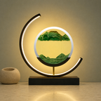 Green quicksand table lamp with a black frame glowing on a cream stone surface.
