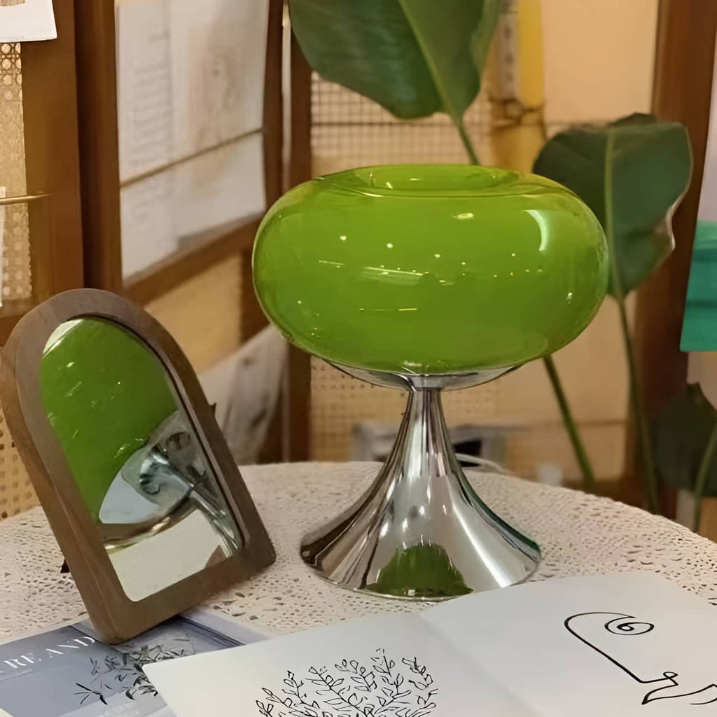 Green donut table lamp beside a mirror and books.
