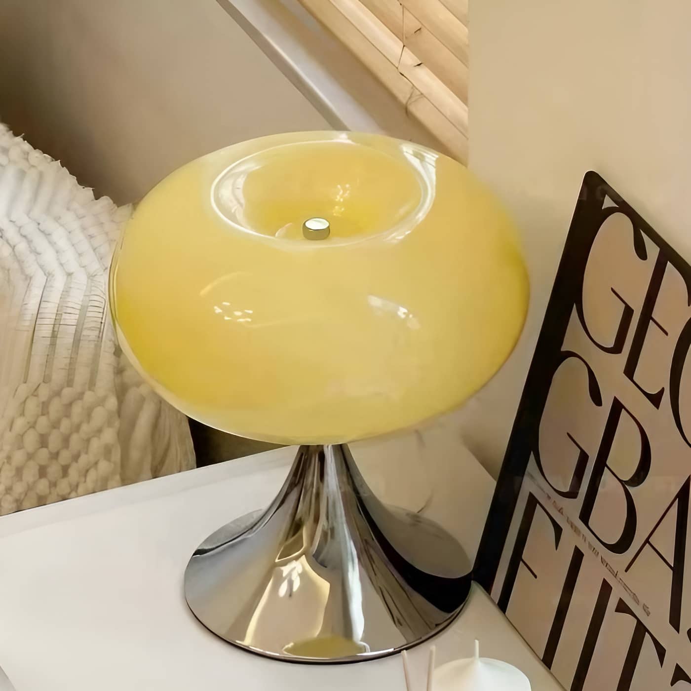 Beige donut table lamp viewed from above beside a framed print.