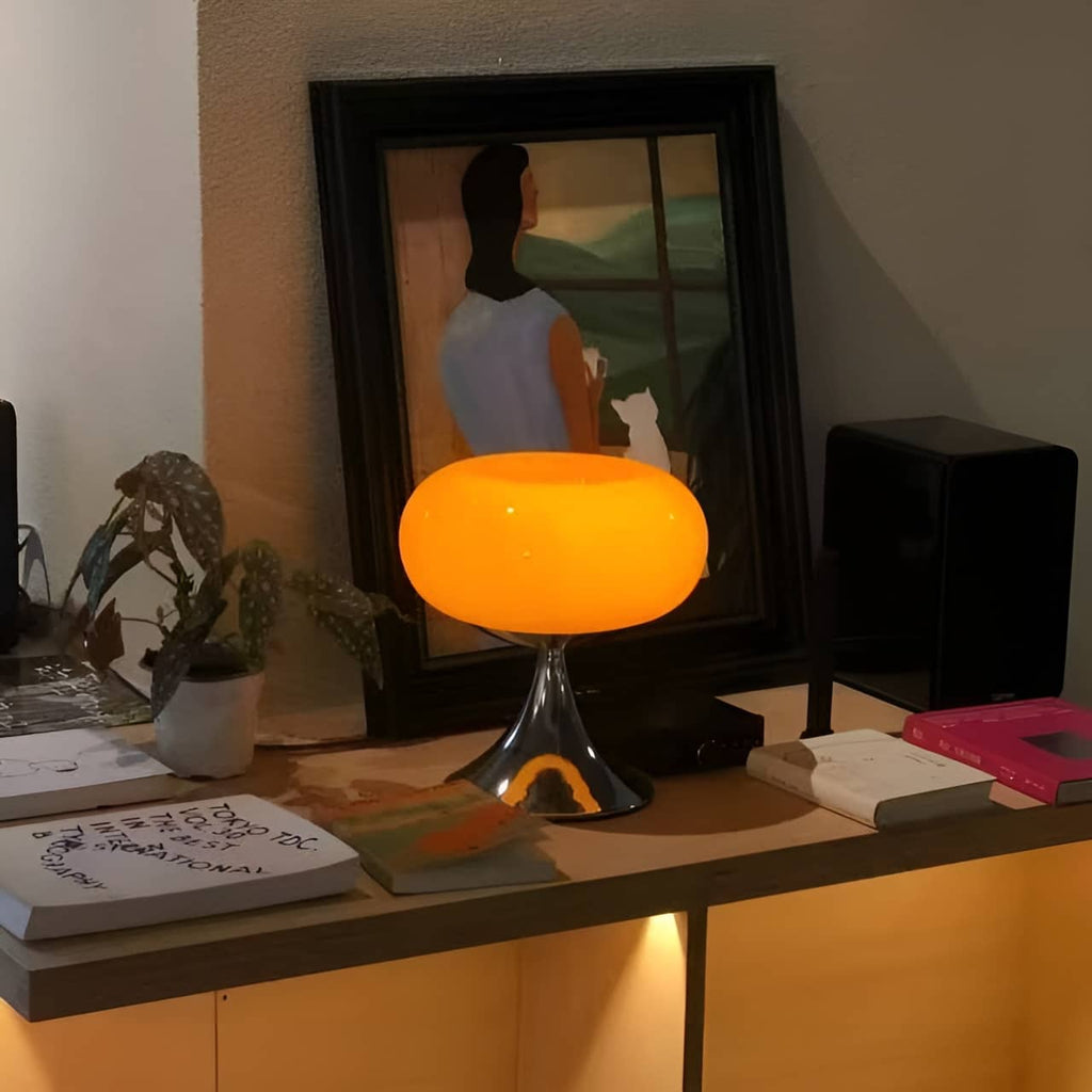 Orange donut table lamp lit on a cabinet beside decorative objects.