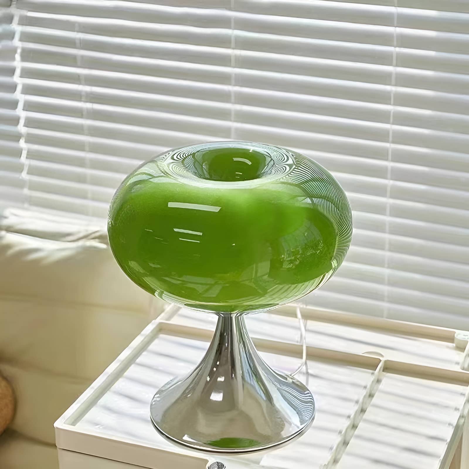 Green donut table lamp on a window-side white trolley.