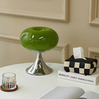 Green donut table lamp beside a glass and patterned tissue holder.