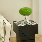 Green donut table lamp on a black cabinet with a checkerboard top.