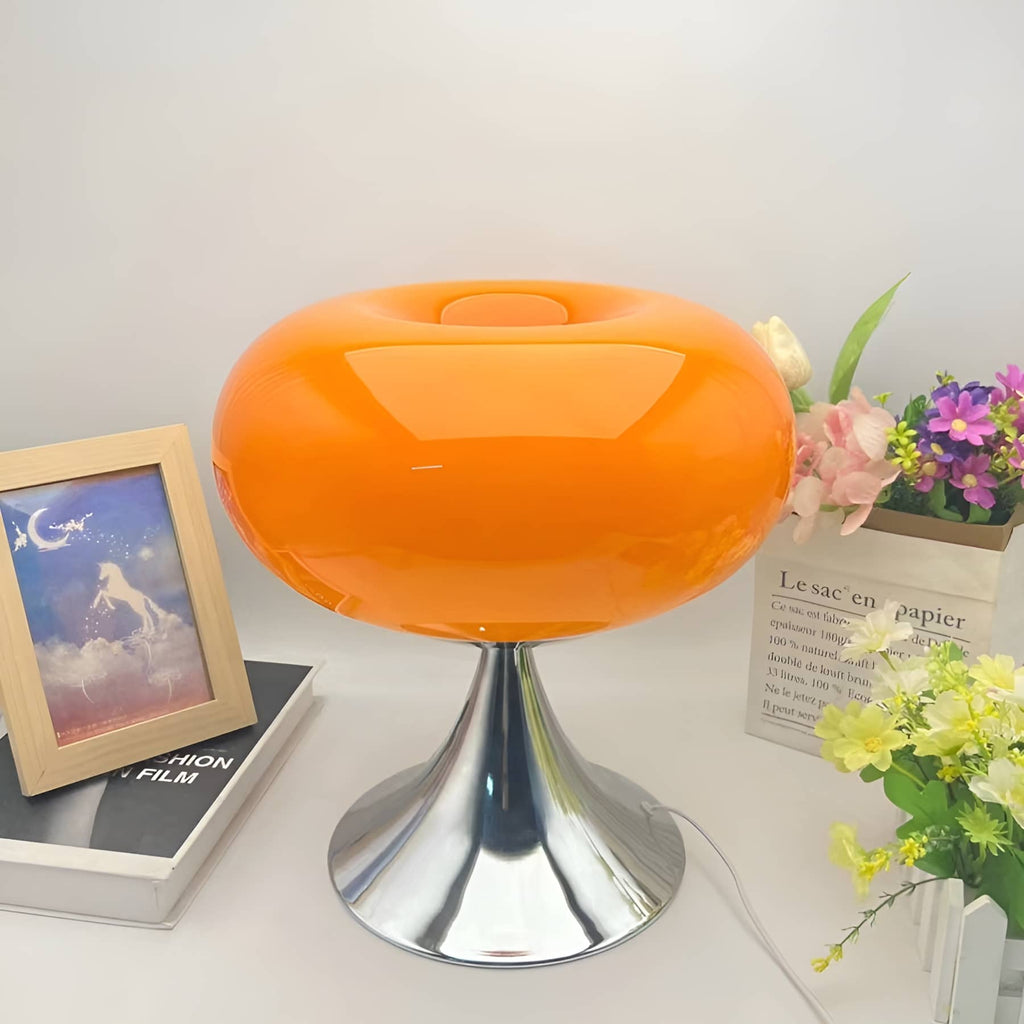 Orange donut table lamp beside flowers and framed artwork.
