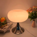 Pink donut table lamp glowing warmly beside a vase of flowers.