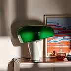Green marble table lamp lit beside colorful framed artwork.