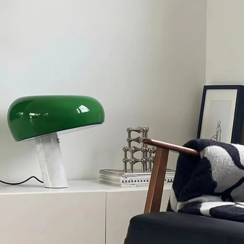 Green marble table lamp on a white sideboard near an armchair.