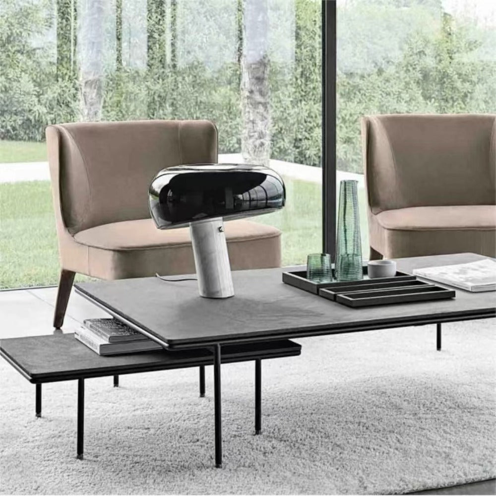 Black marble table lamp on a coffee table in a window-lined sitting area.