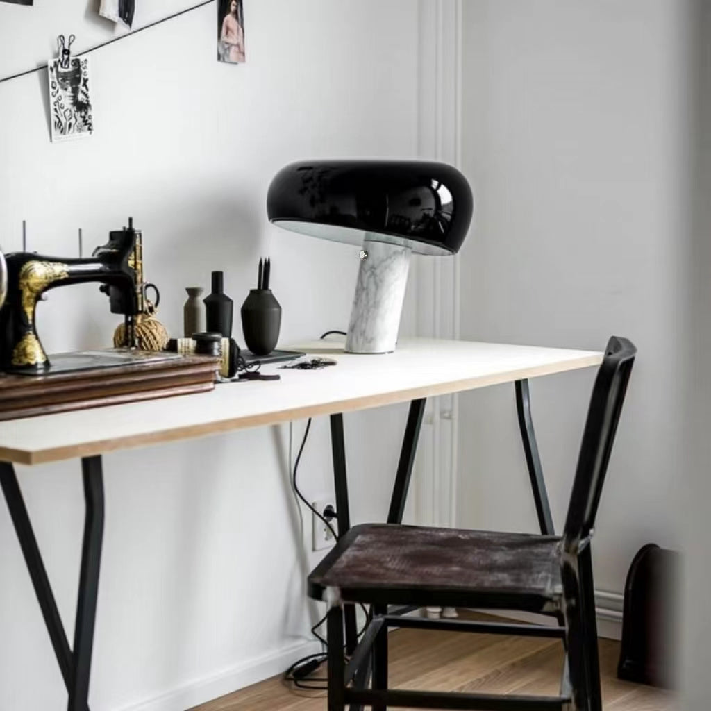Black marble table lamp beside a sewing machine on a work table.
