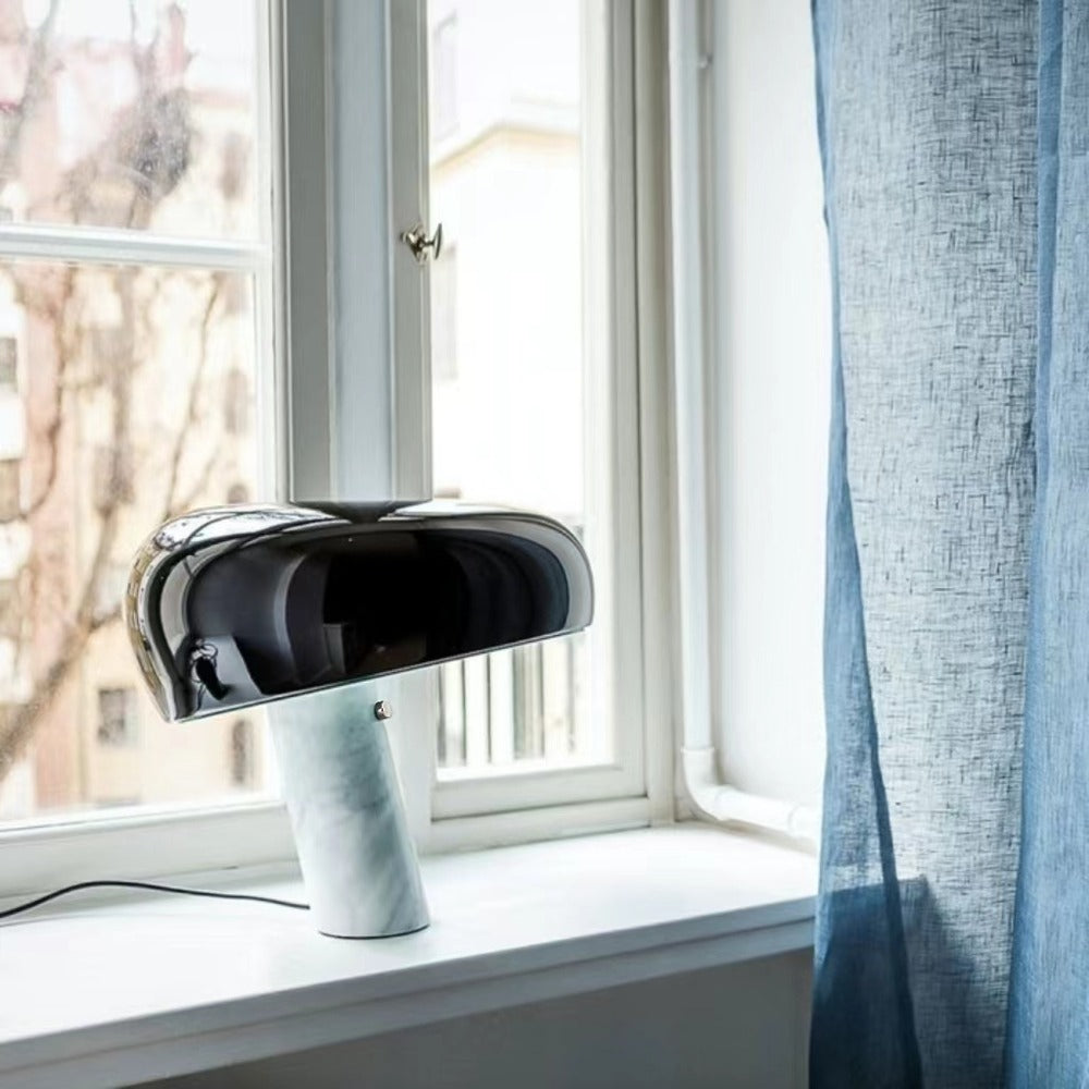 Black marble table lamp on a window ledge beside a blue curtain.
