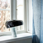 Black marble table lamp on a window ledge beside a blue curtain.