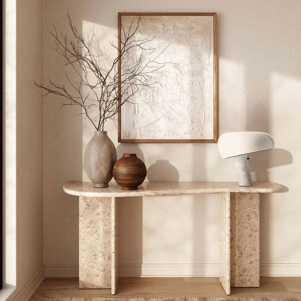 White marble table lamp on a stone console beside ceramic vases.