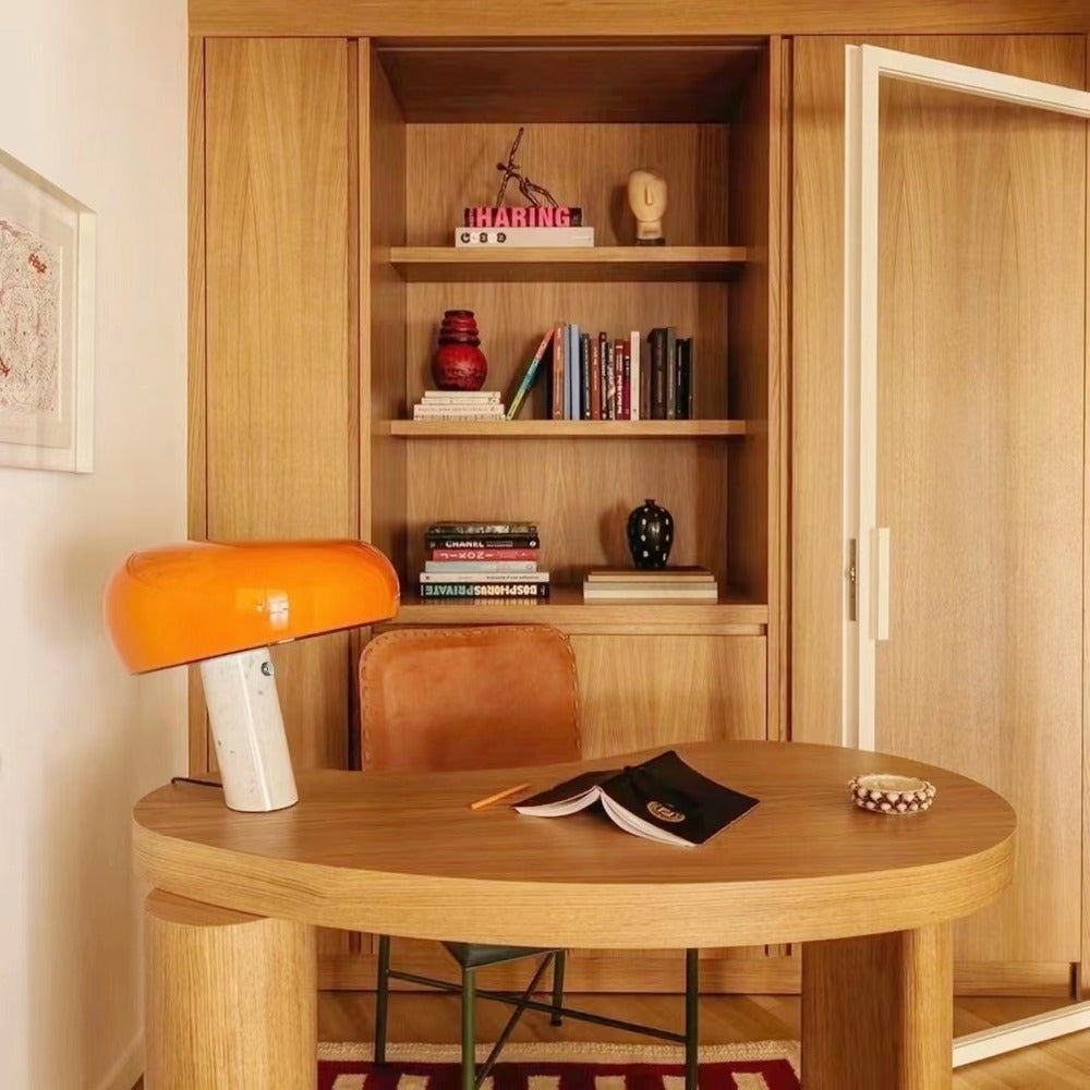 Orange marble table lamp on a round wood table in a reading corner.