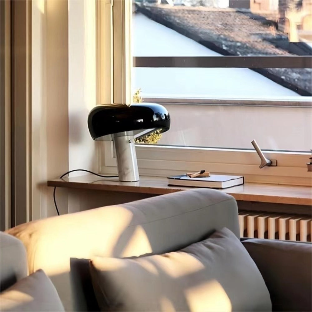 Black marble table lamp on a desk beside a window and chair.