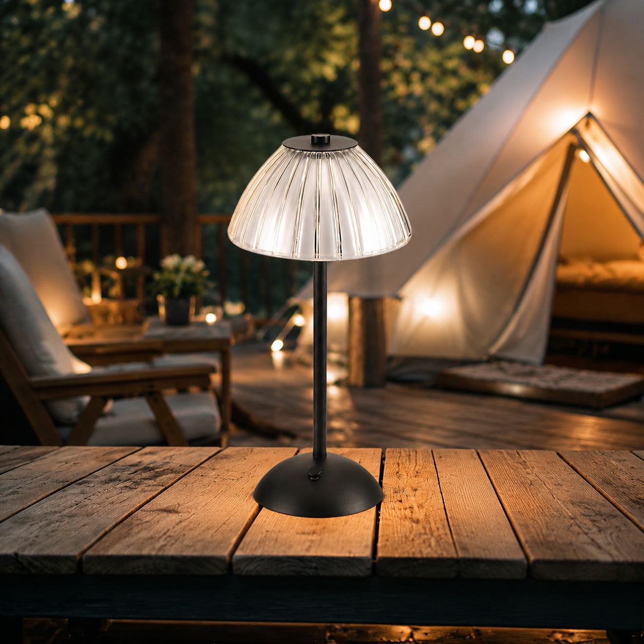 Black rechargeable table lamp glowing on a deck beside a camping tent.