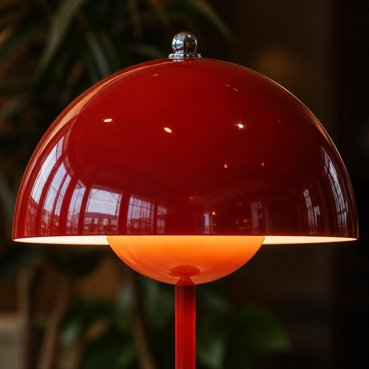 Close-up of the red table lamp dome showing its glossy surface, top fitting, and warm underside glow.