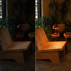 Red table lamp glowing on a small side table between wooden lounge chairs in a dark seating area.