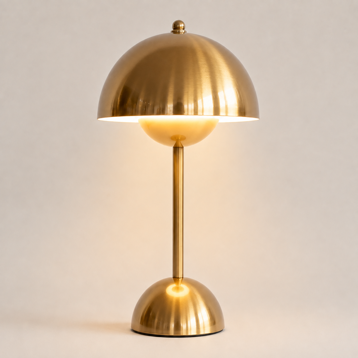 Gold table lamp with a rounded dome shade, slim stem, circular base, and warm downward glow.