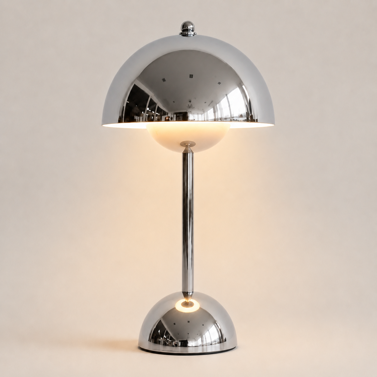 Silver table lamp with a rounded dome shade, slim stem, circular base, and warm downward glow.