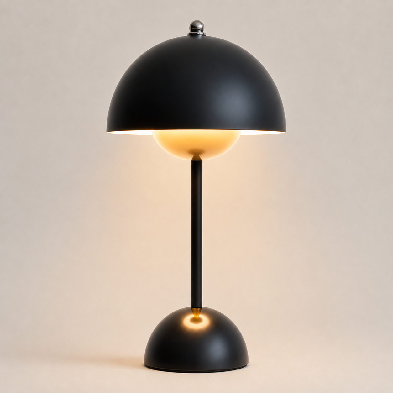 Black table lamp with a rounded dome shade, slim stem, circular base, and warm downward glow.