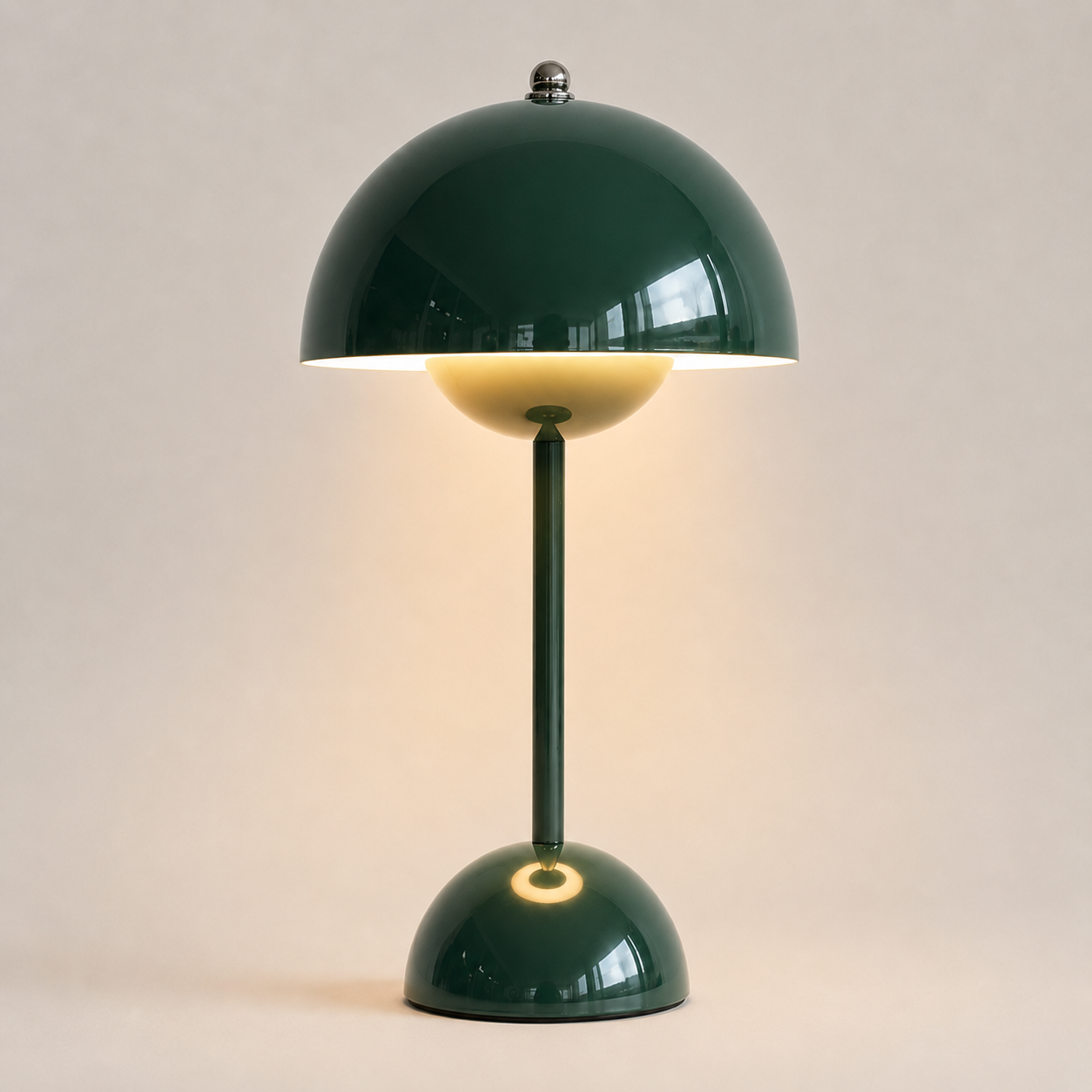Dark green table lamp with a rounded dome shade, slim stem, circular base, and warm downward glow.