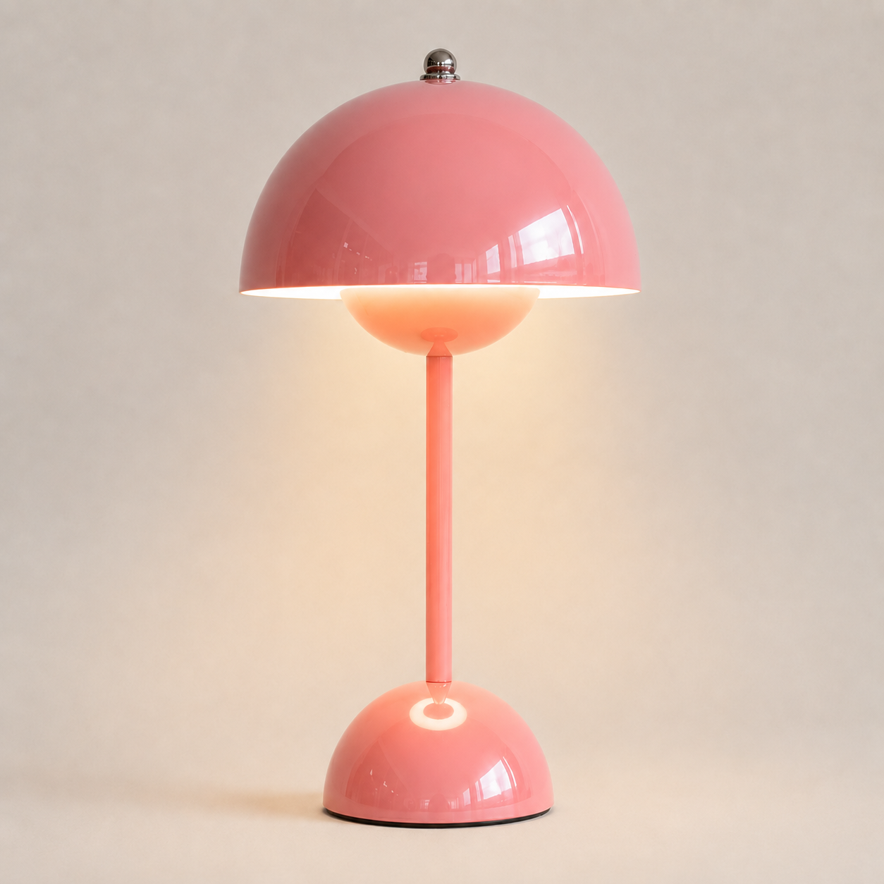 Pink table lamp with a rounded dome shade, slim stem, circular base, and warm downward glow.