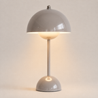 Gray table lamp with a rounded dome shade, slim stem, circular base, and warm downward glow.
